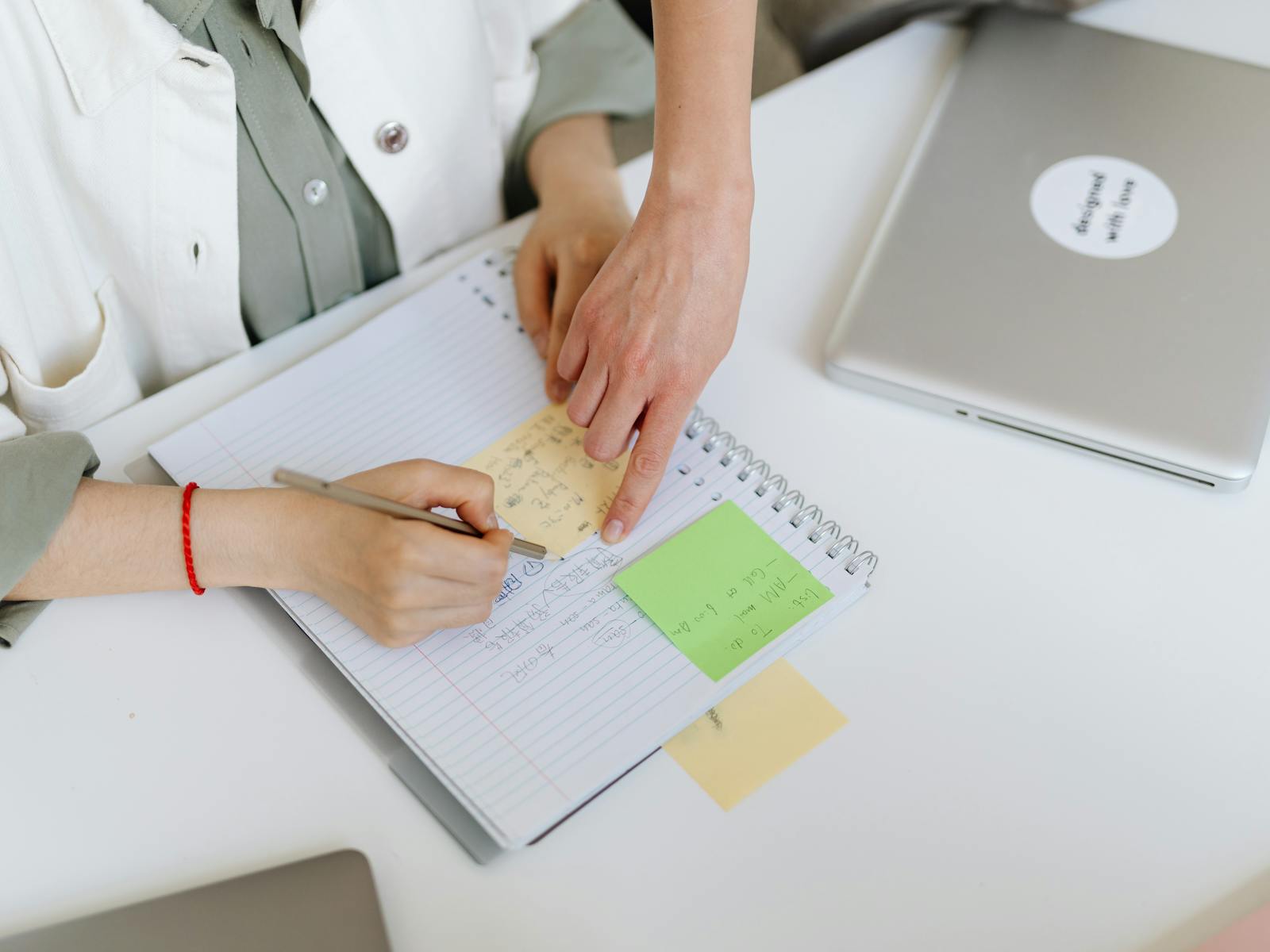 Person skriver anteckningar med post-its och laptop